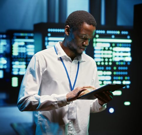 Technician walking through server rigs Technician in high tech facility walking through server rigs used for computationally intensive tasks such as molecular modeling or physical simulations. Specialist doing routine equipment maintenance